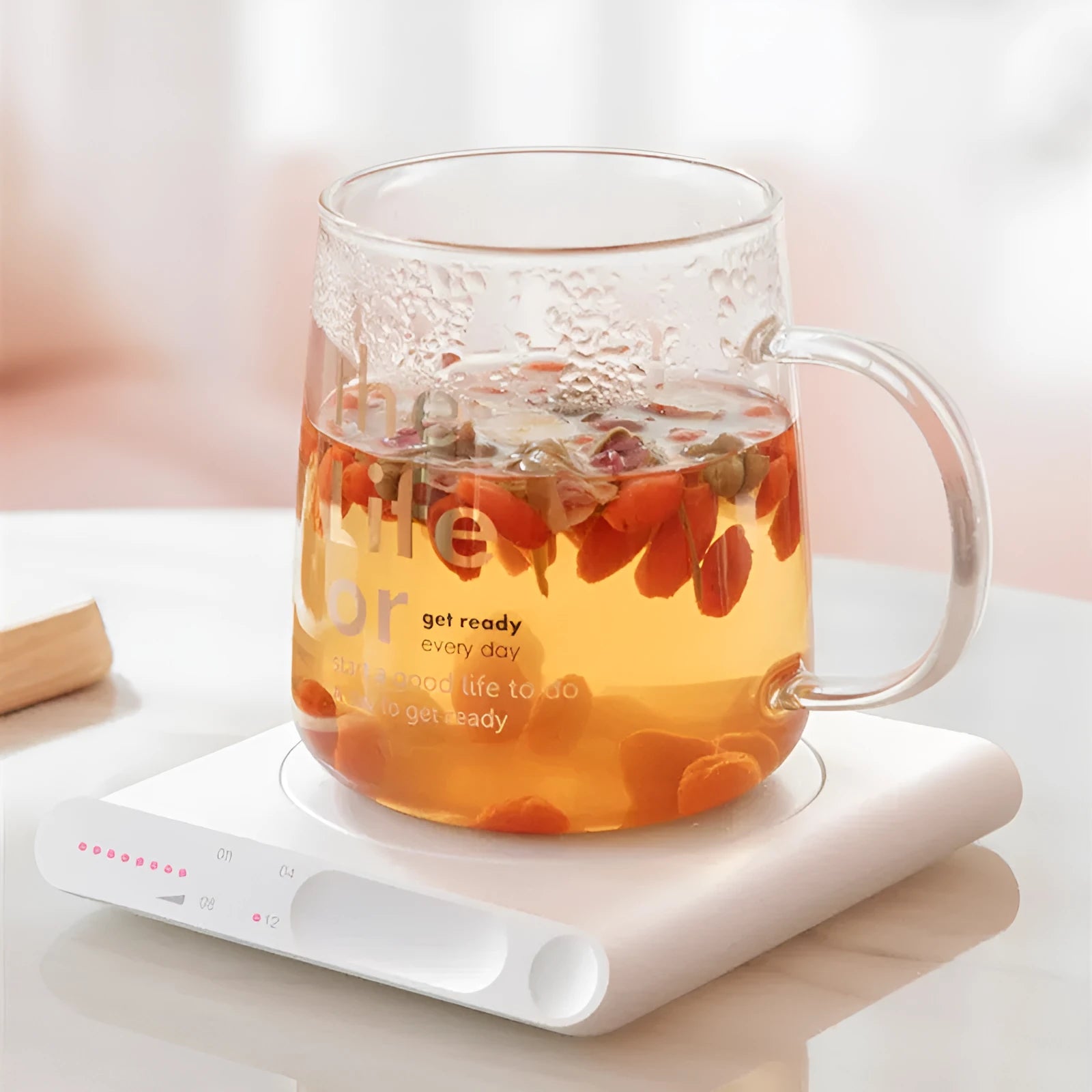 Pink and white USB heating cup pad or mug warmer with mechanical controls on a desk.