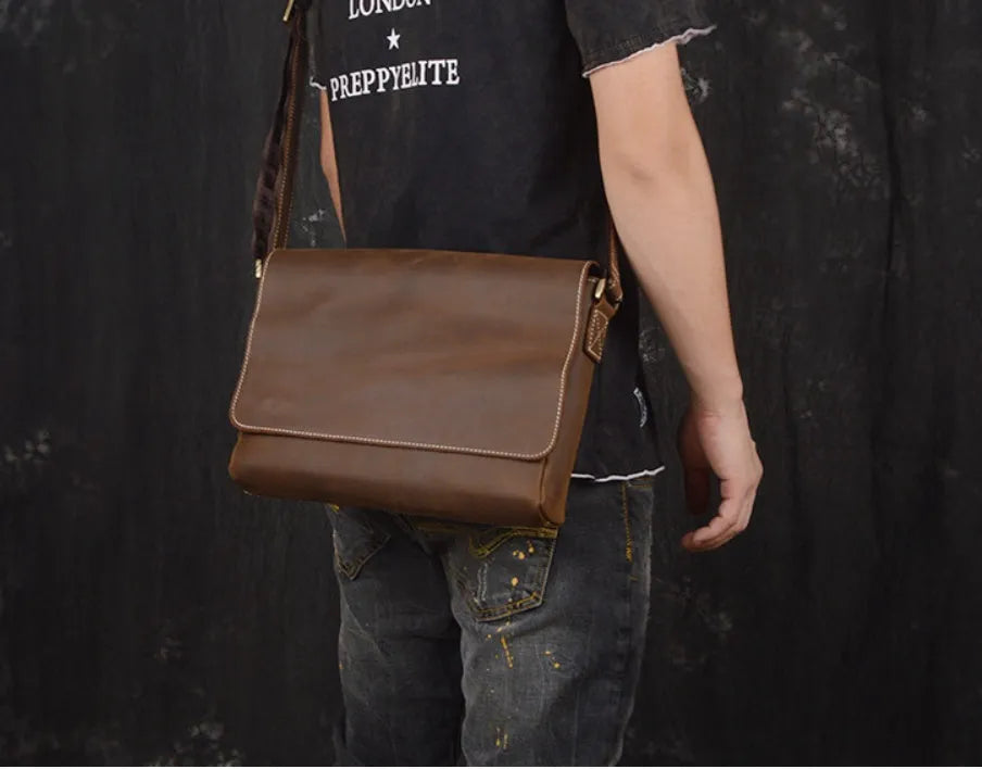 Vintage brown cowhide men's messenger bag showing front flap and adjustable shoulder strap