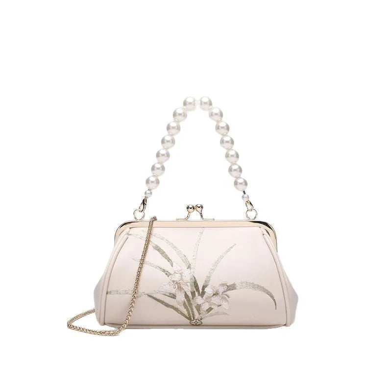 Beige women's shoulder bag with embroidered detailing and a soft, shell-shaped design.