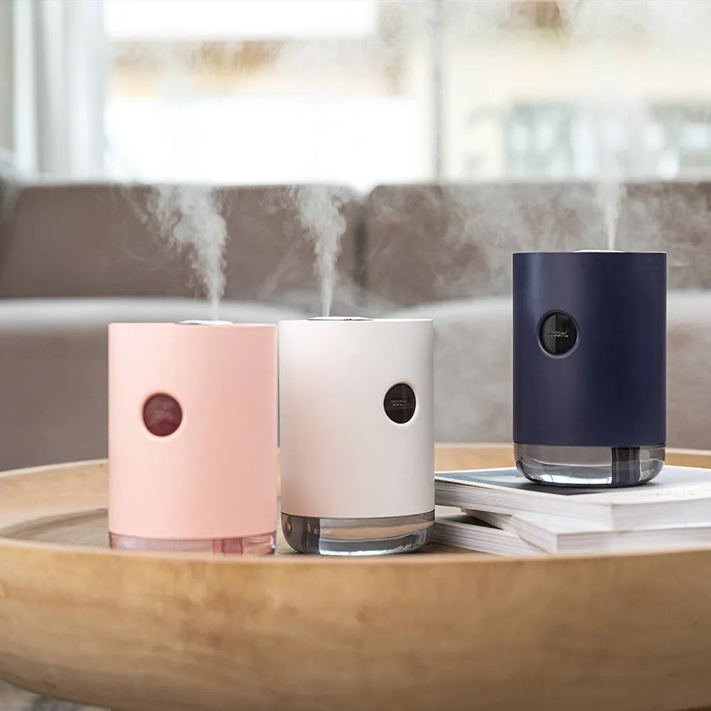 A blue wireless humidifier with a USB cable on a wooden desk.