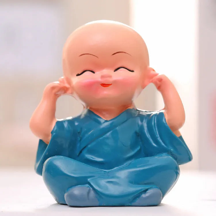 Set of 4 miniature resin Buddha monk statues in blue, brown, gray, and orange, 4.7 cm tall, on a shelf