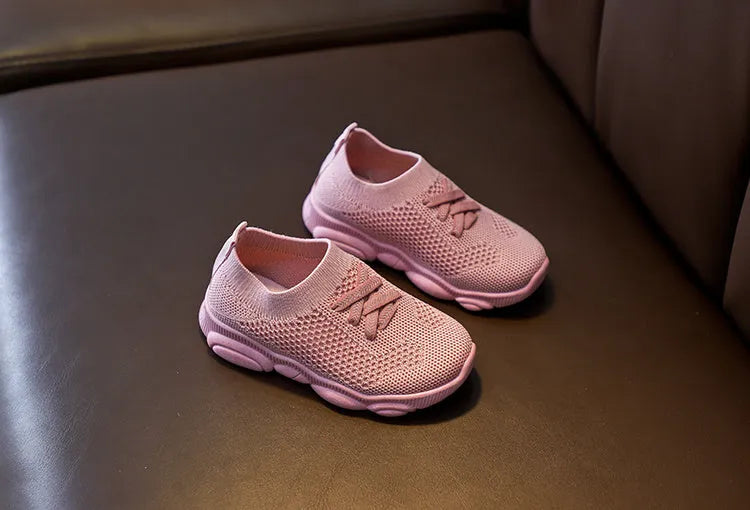Children's fabric lazy shoe with a non-slip rubber sole, shown in colour options of white, black, pink, and grey.