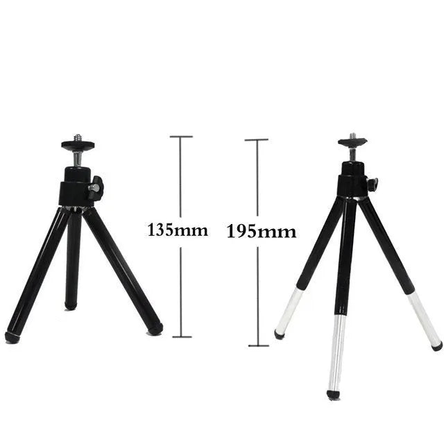 Black mini flexible tripod extended on a table with a silver U-shaped phone clip attached.