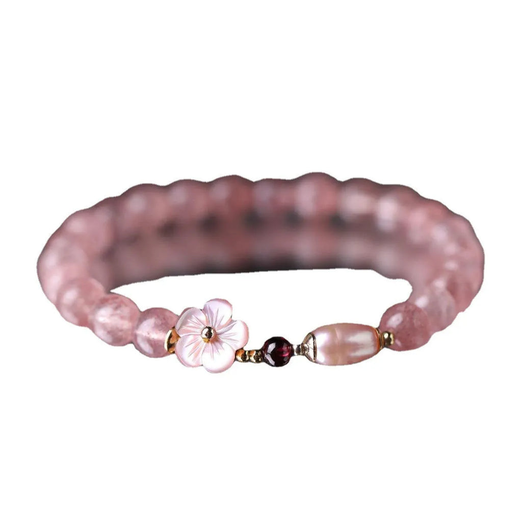 Women's strawberry quartz peach blossom crystal bracelet with floral design on wrist.