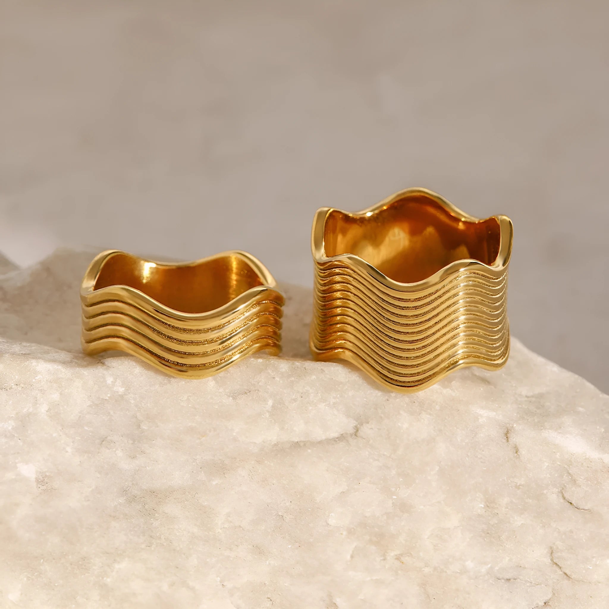 Stainless steel ring with a geometric wave pattern on a wide band, showing two colour options.