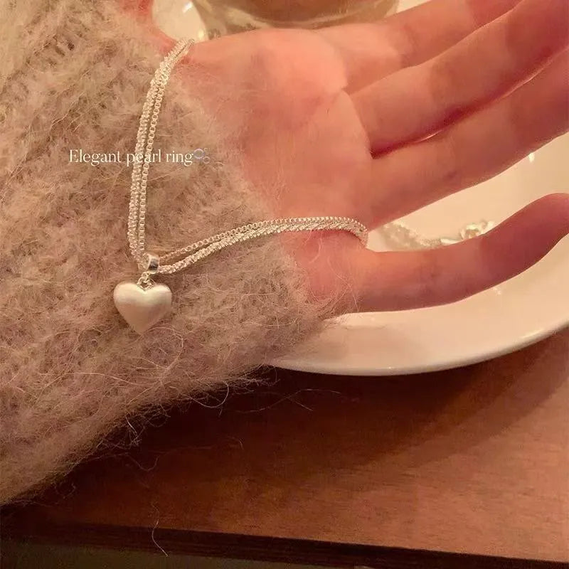 Women's brushed silver double-layer heart pendant necklace on an adjustable chain.