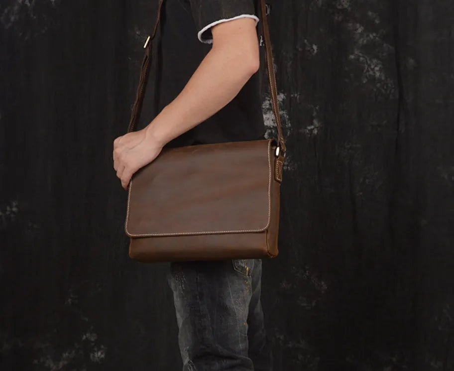 Vintage brown cowhide men's messenger bag showing front flap and adjustable shoulder strap