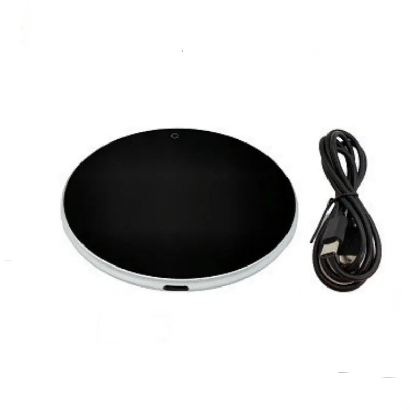 Black USB heating coaster pad for cups with LED indicator light on a wooden desk.
