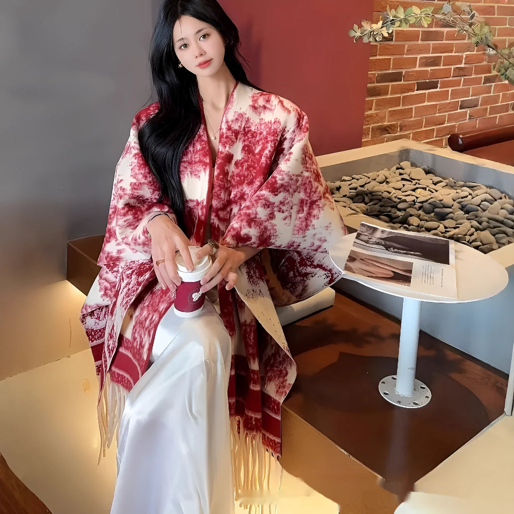 Woman wearing a printed tassel-trim scarf cape draped over shoulders.