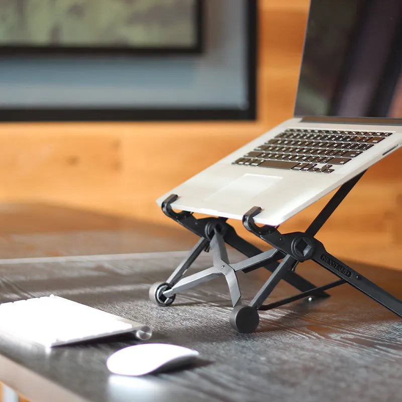 Black folding portable laptop stand made from reinforced nylon, shown folded to its compact size.