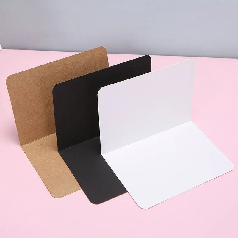 Pack of 100 plain kraft folded greeting cards in black, brown, and white, sized 10 by 15 cm.