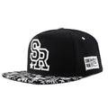 Black and white cotton baseball cap with embroidered letter design on the front.