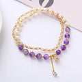 Close-up of a women's double ring bracelet with a freshwater pearl and amethyst crystal beads on a wrist.