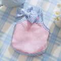 Small dog wearing a blue elastic vest with bow suspenders and a raised heart texture design.