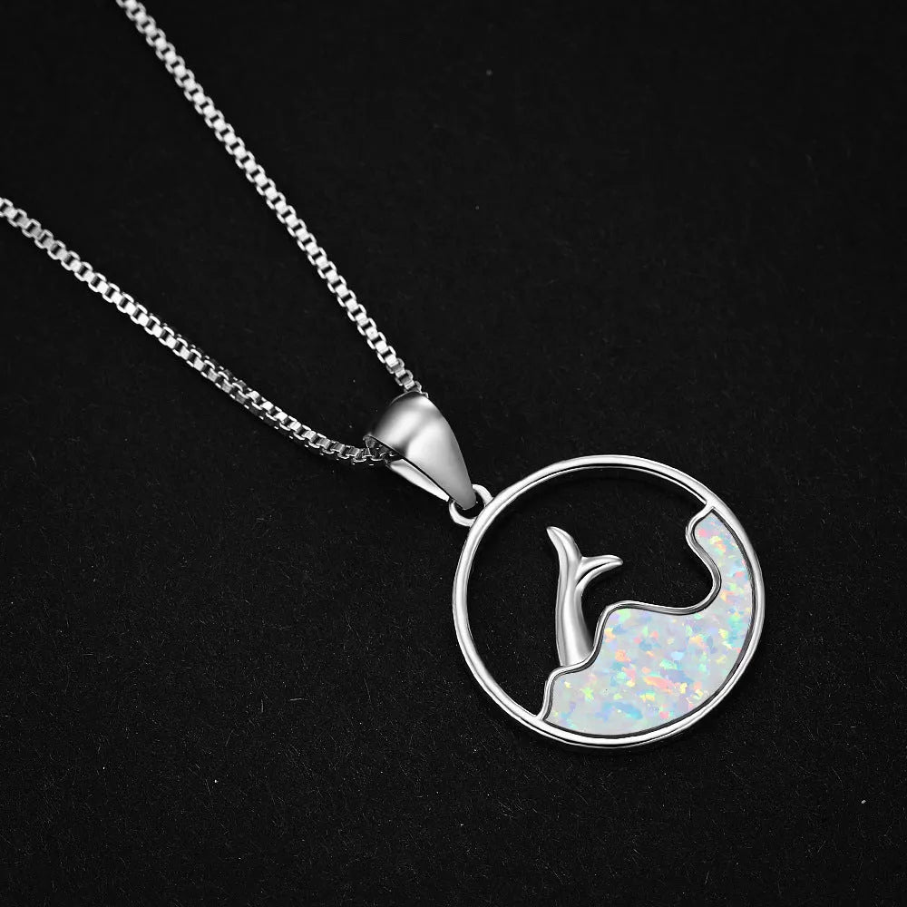 A woman's copper necklace with a round, geometric sea fishtail pendant in a blue opal colour finish.