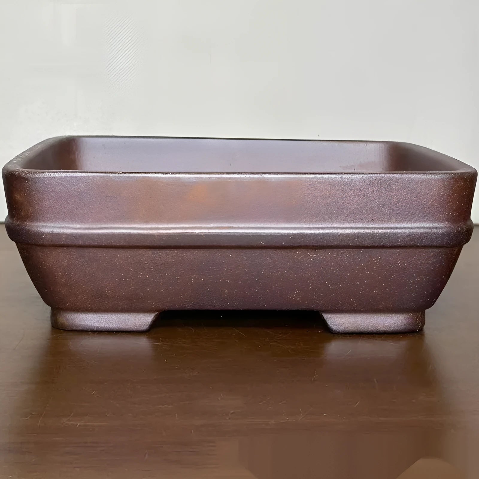 Light brown rectangular ceramic bonsai flower pot on a wooden surface