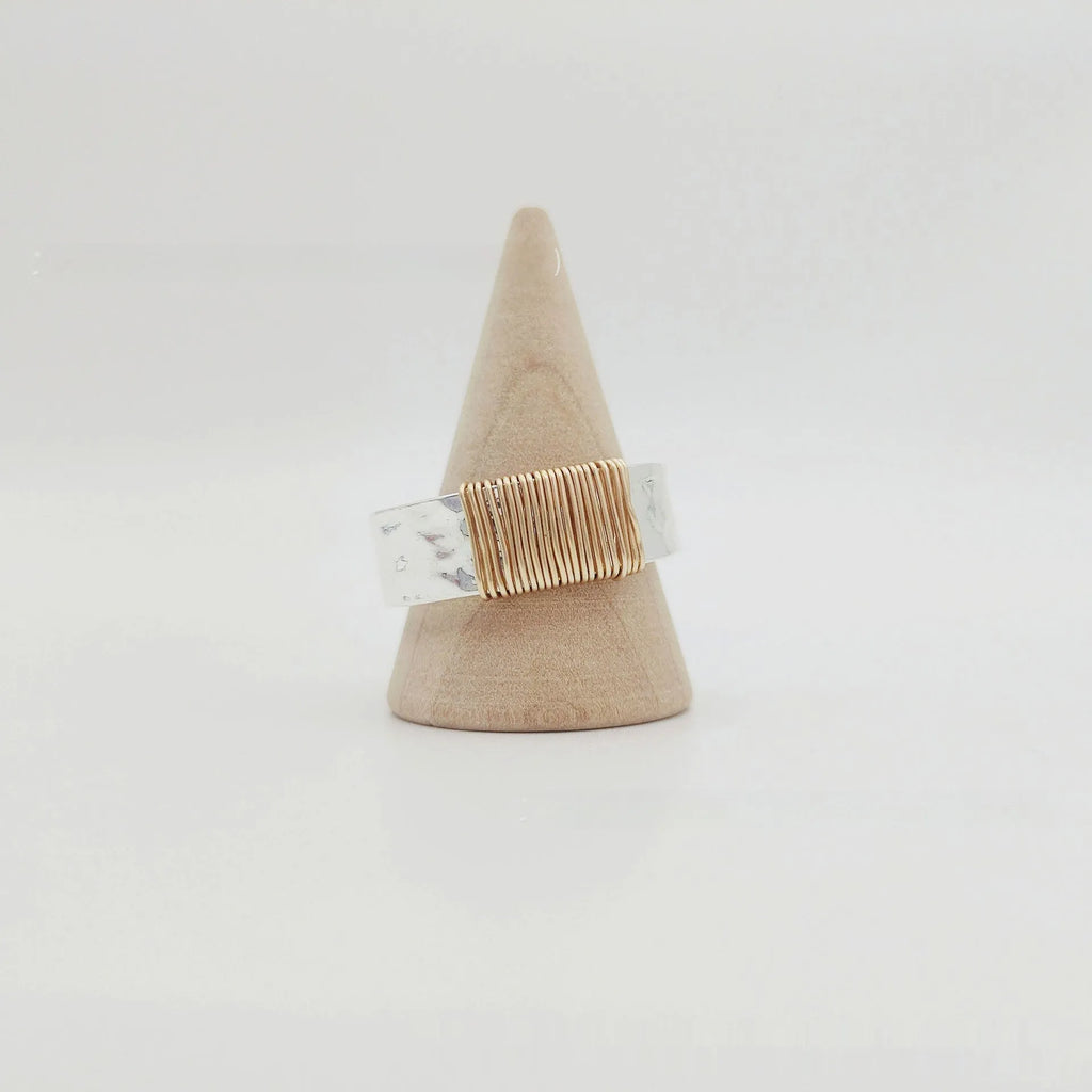 Geometric copper ring bracelet with a wide face and irregular coil design in a silver gold colour.