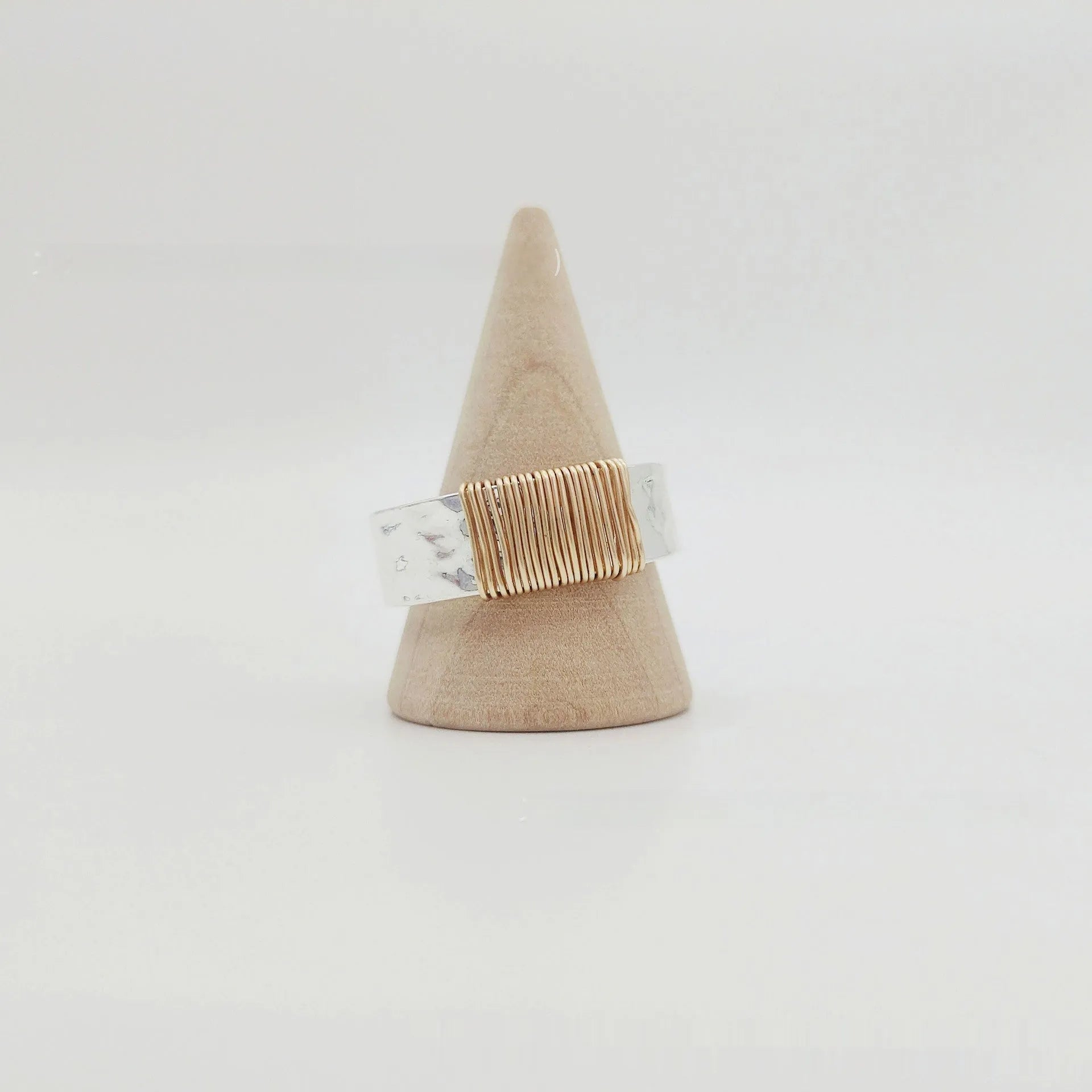 Geometric copper ring bracelet with a wide face and irregular coil design in a silver gold colour.