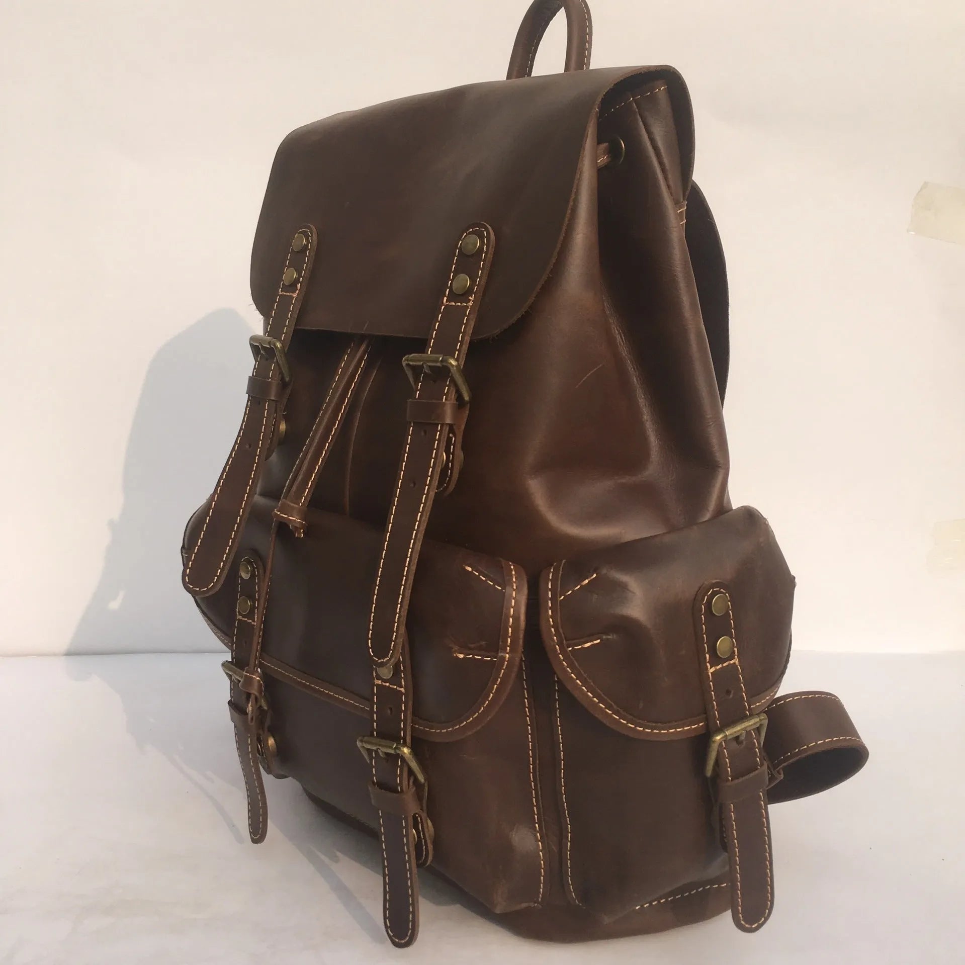Brown men's leather backpack with an air-pillow belt system on the back.
