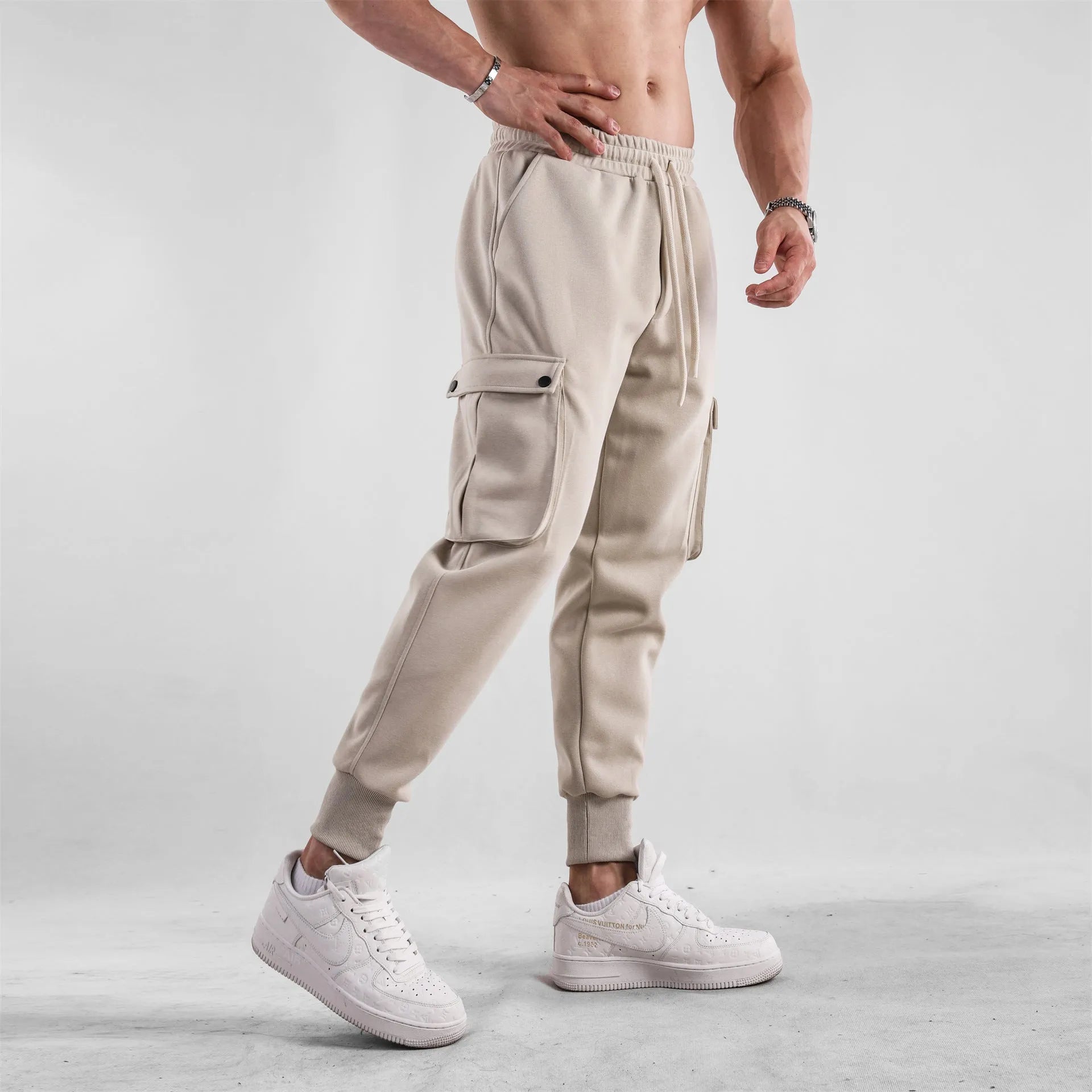 Man wearing loose light grey cotton trousers with ankle-tied cuffs and multiple pockets.