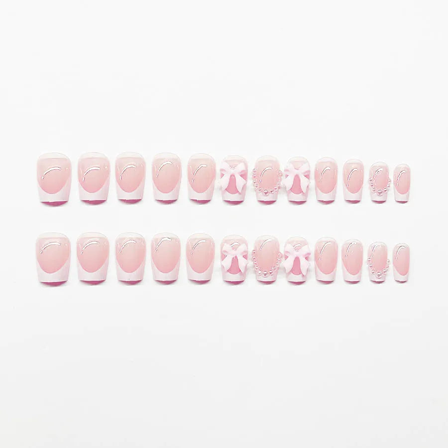 Short white French tip false nails with cute bow and starry sky designs, shown with glue bottles.