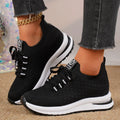 Black and white women's flat lace-up mesh sneakers with round toe on a rubber sole.