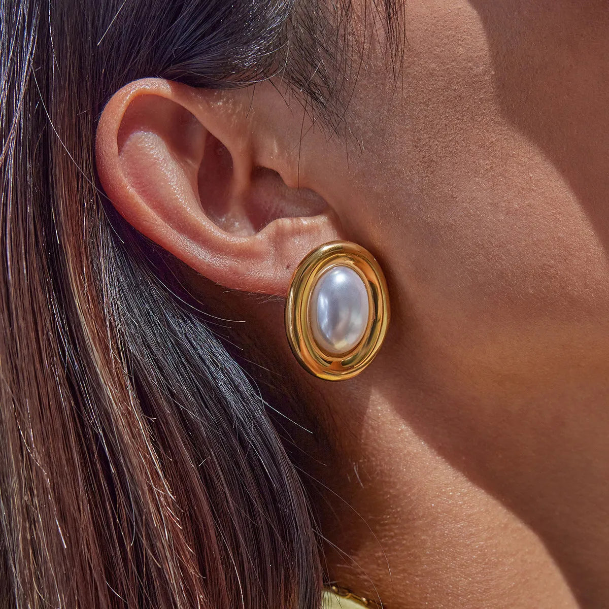 A pair of stainless steel vintage pearl stud earrings with a round pearl and electroplated finish.