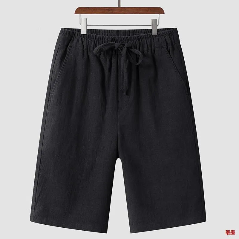 Men's beige linen shorts with loose cropped leg and elasticated waistband on a neutral background.