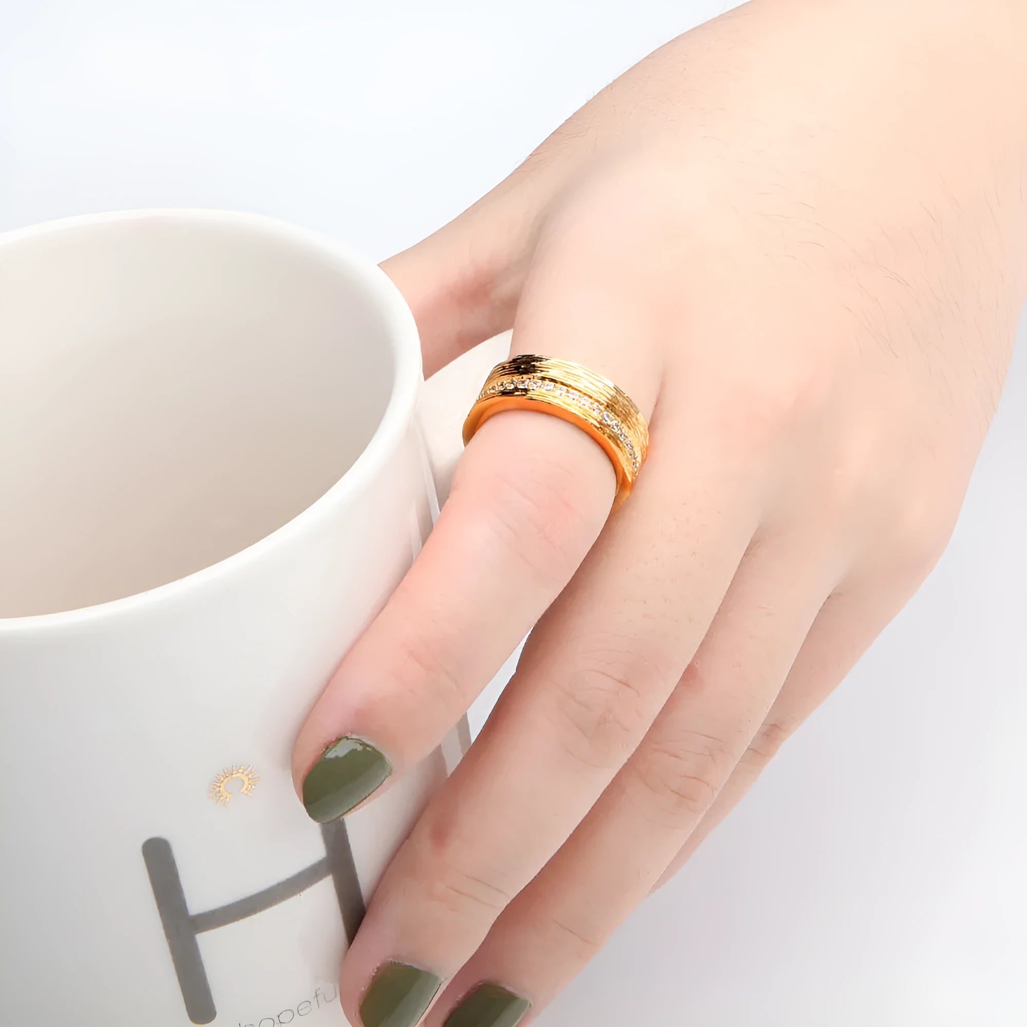 Geometric gold-colour copper ring with zircon stone on a grey background.