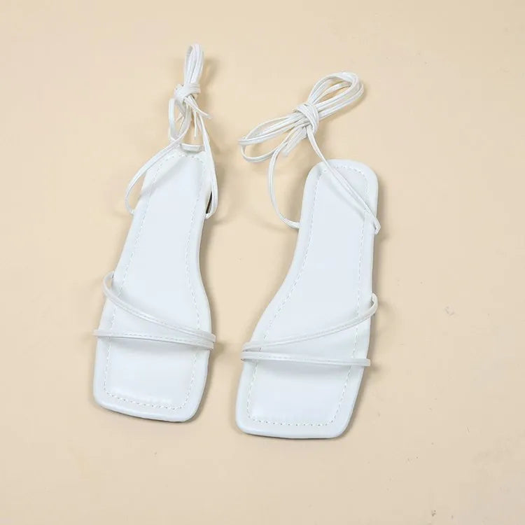 Women's white flat sandals with ankle bandage strap and front lace-up on a square toe.