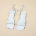Women's white flat sandals with ankle bandage strap and front lace-up on a square toe.