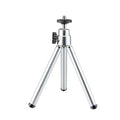 Black mini flexible tripod extended on a table with a silver U-shaped phone clip attached.