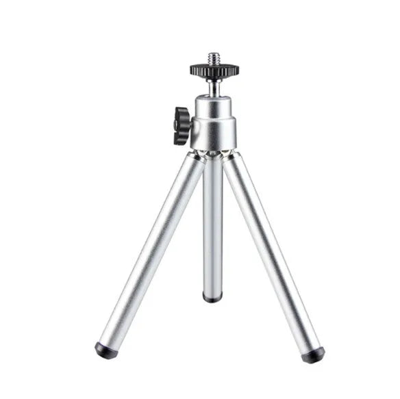 Black mini flexible tripod extended on a table with a silver U-shaped phone clip attached.