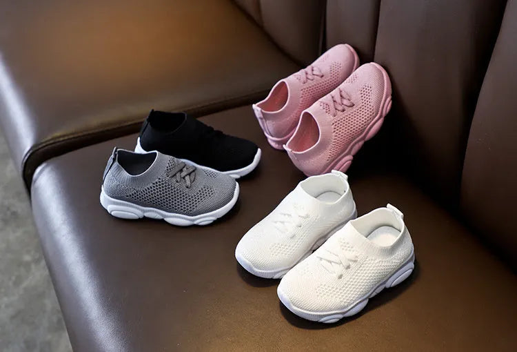 Children's fabric lazy shoe with a non-slip rubber sole, shown in colour options of white, black, pink, and grey.