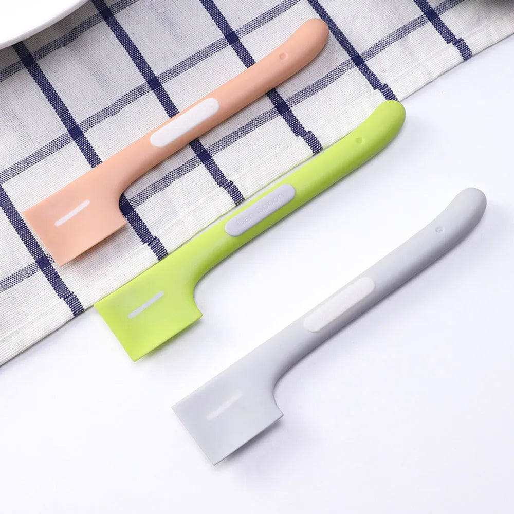 Green pet feeding spoon with long handle and right-angle edge for scraping canned dog or cat food.