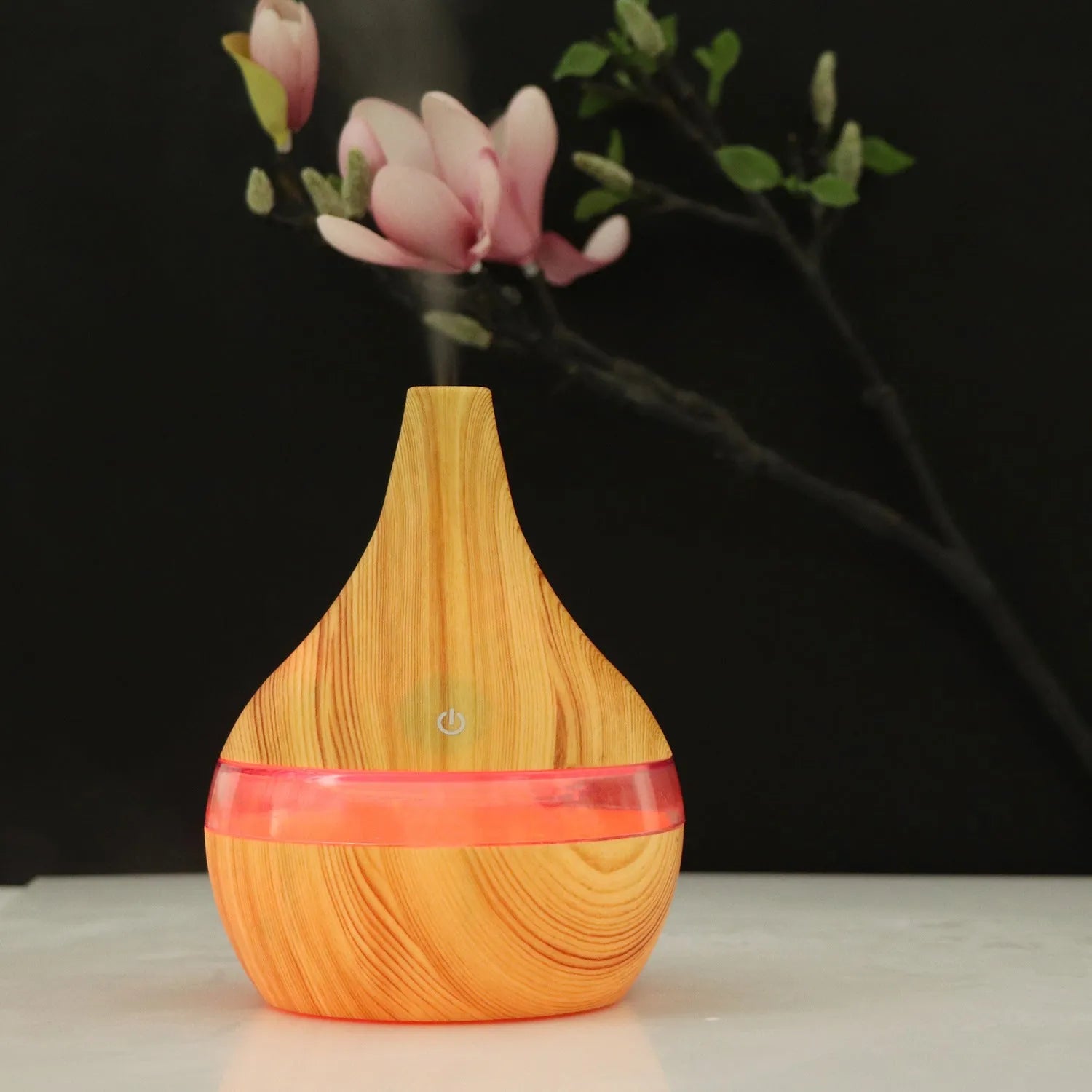 A columnar USB air humidifier with a wood grain finish, remote control, and USB cable on a desktop.