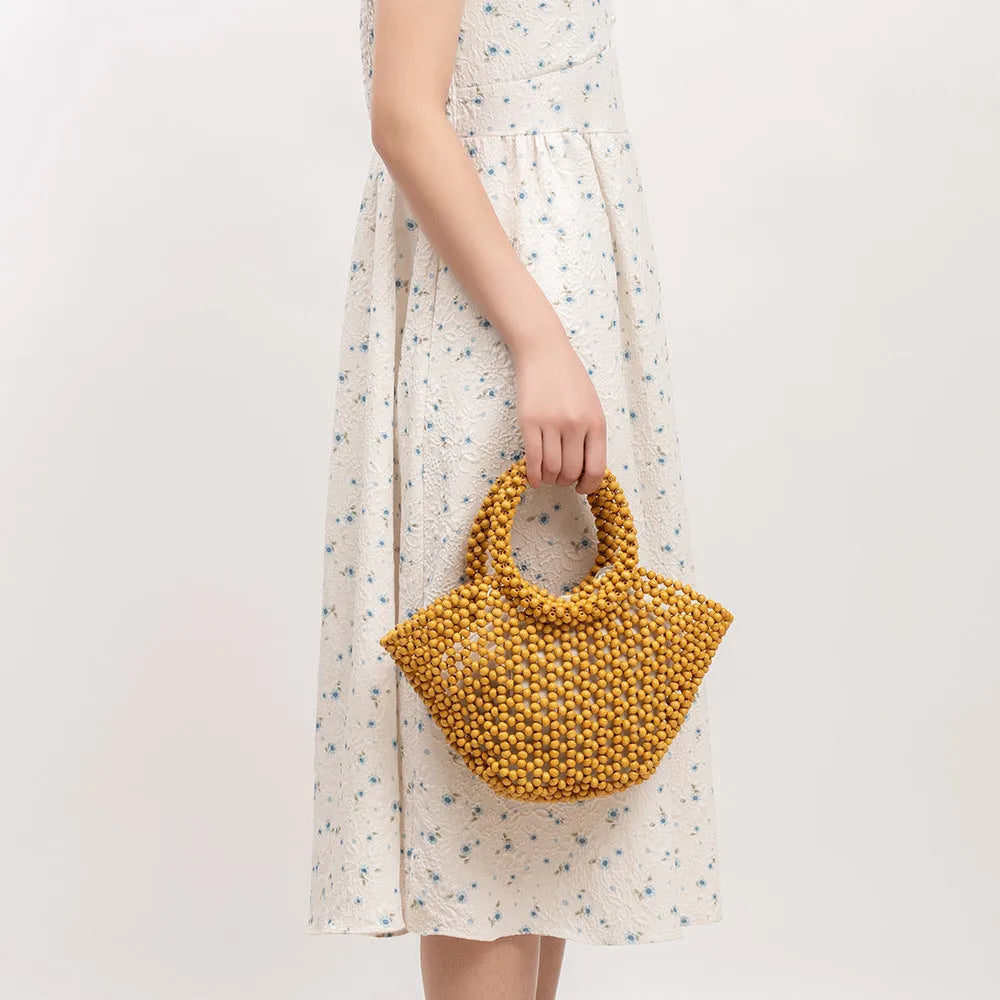 Hand-woven dumpling-shaped beach bag with wooden beads in milky white.