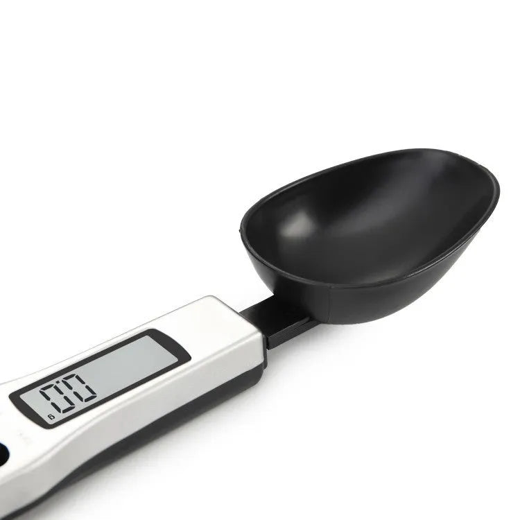 Smart digital measuring spoon with integrated display showing weight, next to AAA batteries.