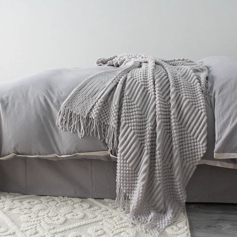 Small light grey polyester throw blanket folded on a sofa, showing its compact 127x170cm size.