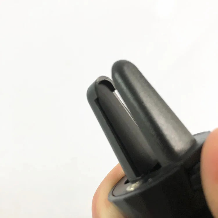 Black car phone holder clipped to vehicle air vent holding smartphone for navigation