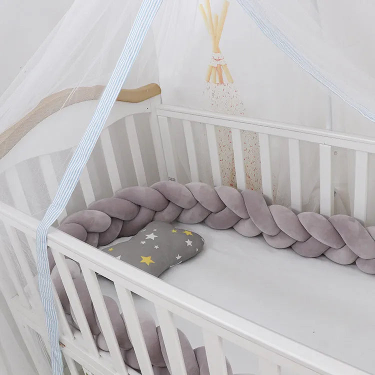 Bendable braid knot baby crib bumper in spandex velvet fabric on a white cot.