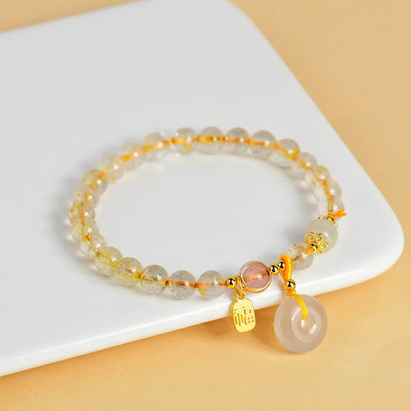 Gold rutilated quartz crystal bracelet with safety buckle and geometric national style design featuring blessing card pendant.