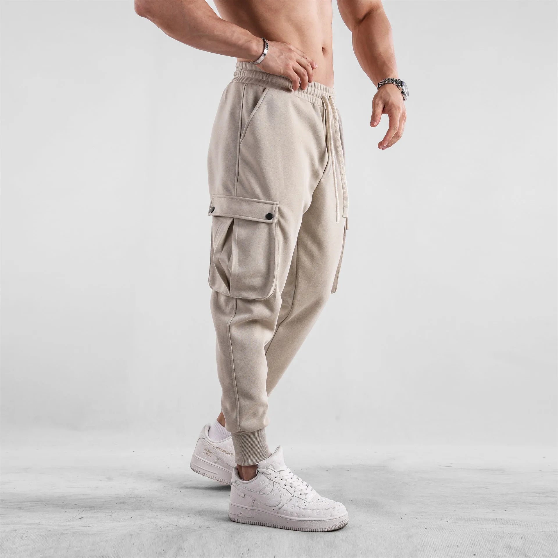 Man wearing loose light grey cotton trousers with ankle-tied cuffs and multiple pockets.