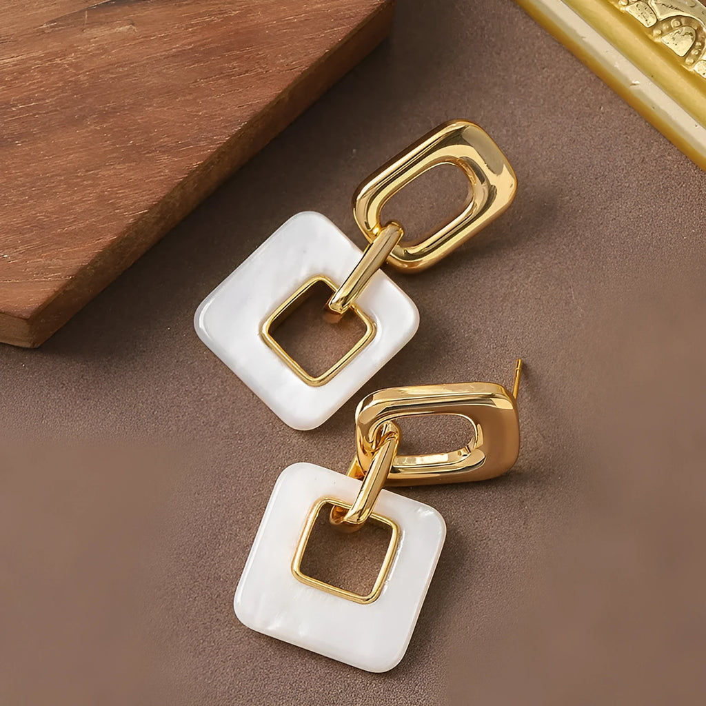 A pair of hollow square geometric earrings with a chamfered edge pattern in a gold tone finish.