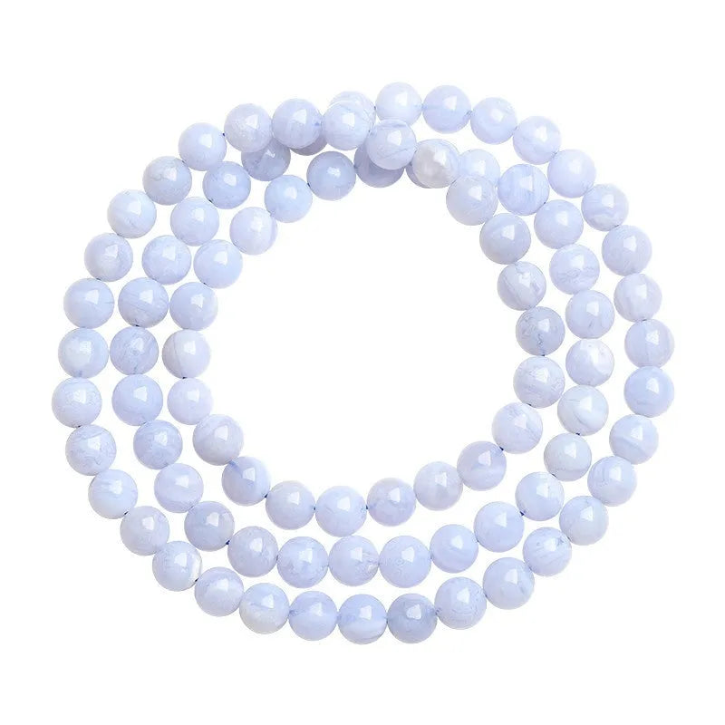 A blue agate bracelet with a natural striped pattern and scattered beads on a wrist.