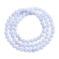 A blue agate bracelet with a natural striped pattern and scattered beads on a wrist.