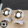Pair of compact USB-powered desktop speakers in black and gold finish beside laptop computer