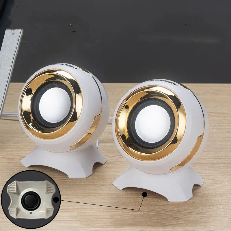Pair of compact USB-powered desktop speakers in black and gold finish beside laptop computer