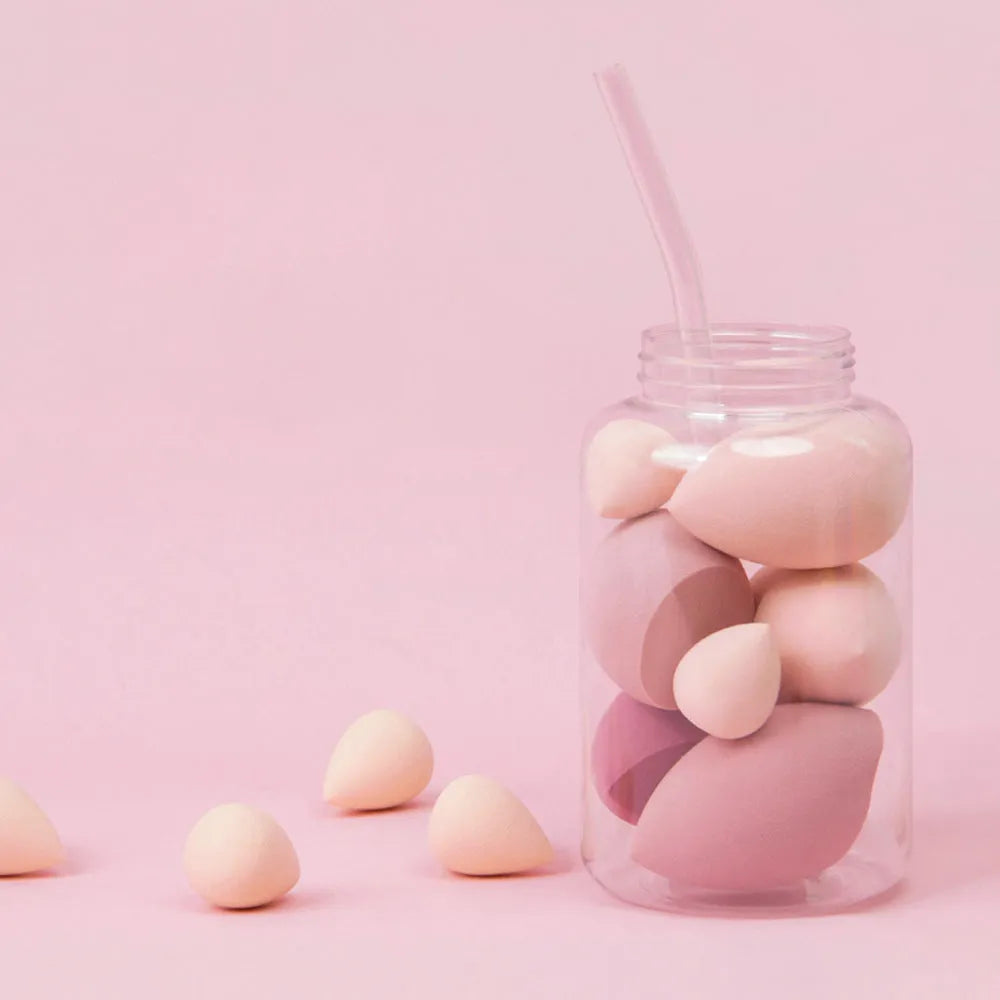 Set of 7 colourful makeup sponge eggs in a transparent jar against a white background