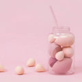 Set of 7 colourful makeup sponge eggs in a transparent jar against a white background